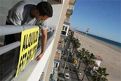 El propietario pone el cartel de se alquila en su apartamento en la costa